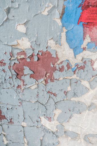 A vertical shot of an old wall with the colorful paint peeling off it