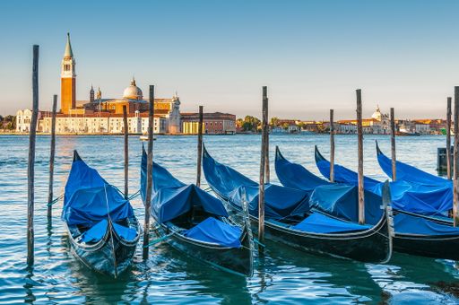 The boats parked in the water surrounded by docks in Venice, Italy and the Church of San Giorgio Maggiore in the background