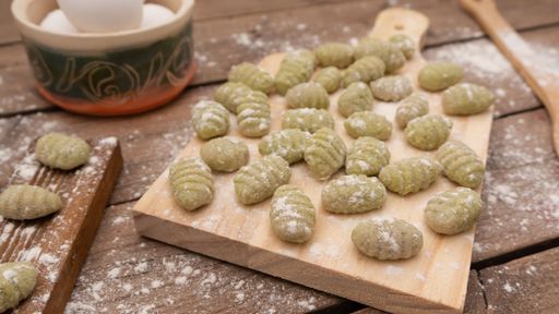 A closeup of Gnocchis on a wooden dock against blurred background