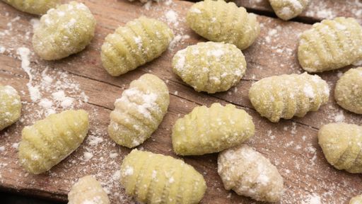 A top view of Gnocchis on a wooden dock with flour on them