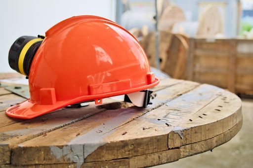 A lifting operator orange safety helmet or hardhat isolated on top of a wooden table.