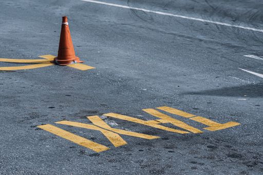 A closeup shot of a traffic cone and "Taxi" written on the asphalt