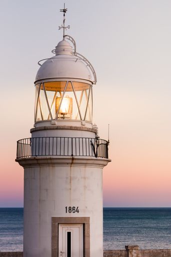 An old lighthouse on the coast with a beautiful sunset in the background