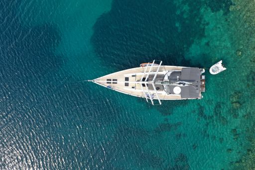 An aerial view of a sailing yacht in a cristally blue sea on a hot sunny day in summer