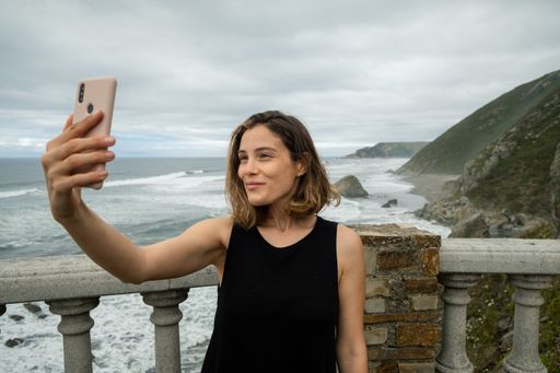 Young woman taking a selfie with a mountainous coast in northern Spain