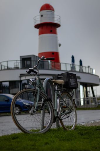 A vertical shot of a bicycle parked near a lighthouse in Rostock, Germany