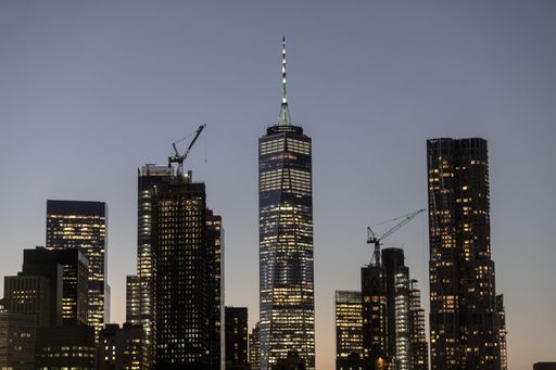 A beautiful picture of modern skyscrapers with lights under a blue sky during sunset