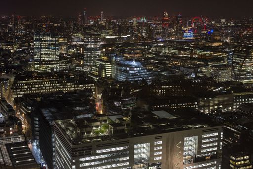 A high shot of modern buildings and lights under a night sky in London from the Broadgate tower