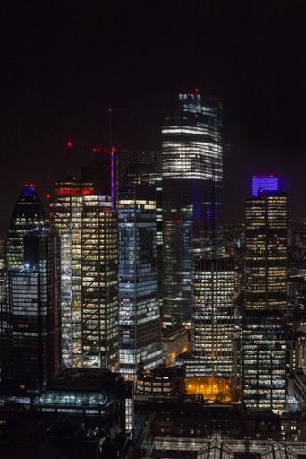 A vertical picture of modern skyscrapers with lights under a night sky in London, the Broadgate tower