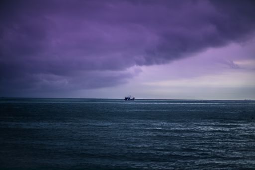 a single ship on the calm sea under the clouds in the evening