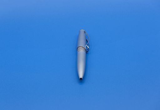 A closeup of a pen isolated on a blue surface under the lights