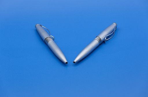 A closeup of two pens isolated on a blue surface under the lights