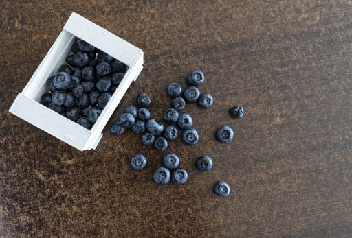 A closeup shot of fresh blueberries in the white box on a wooden background.
