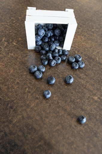 A top view of fresh blueberries in a white box on a wooden background