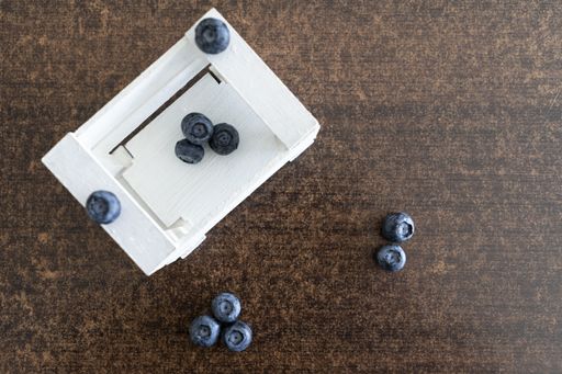 A top view of fresh blueberries in a white box on a wooden background
