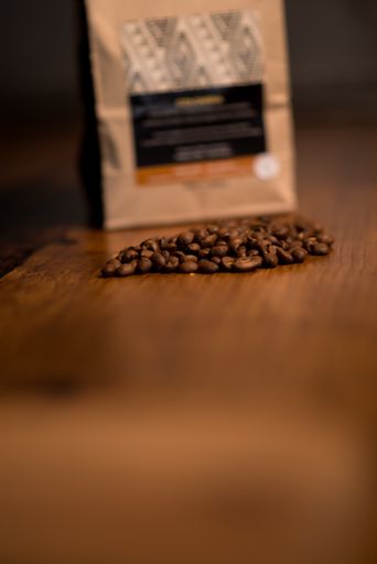 A vertical closeup shot of coffee beans on a wooden table
