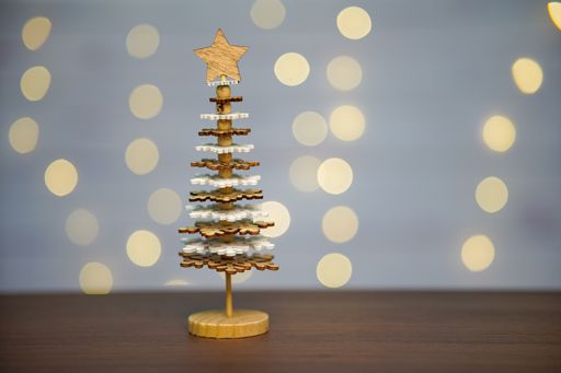 A closeup shot of a small Christmas tree made of snowflakes on a table with bokeh background
