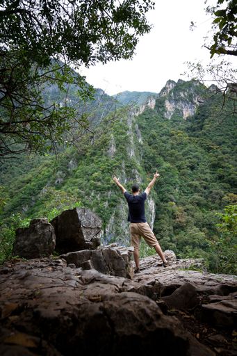 A vertical shot of a man observing the view standing in a rock in La Estanzuela Monterrey Natural Park in Mexico