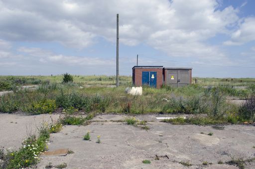 Brownfield land with weeds growing through  asphalt
