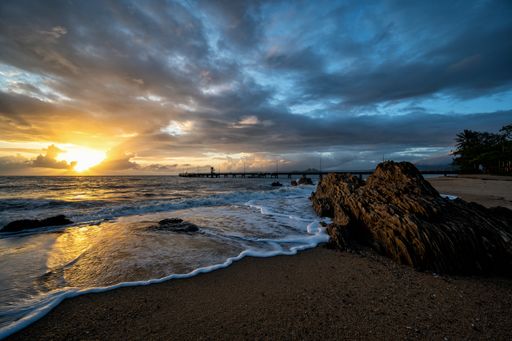 A beautiful shot of the beach at sunset under cloudy sky at Cairns Cape Tribulation Australia