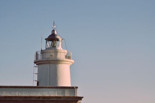 A closeup shot of a lighthouse and the plain blue sky