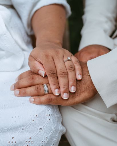 A vertical closeup shot of a bride and groom with their hands with rings held together