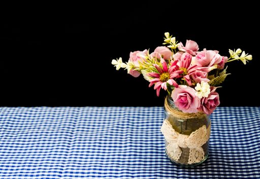 A closeup of a soft floral composition in a vase on the checkered tablecloth