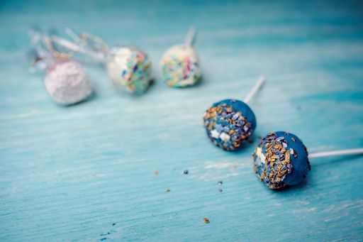 A high angle shot of deliciously decorated pop cakes on a blue surface