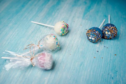 A high angle shot of deliciously decorated pop cakes on a blue surface