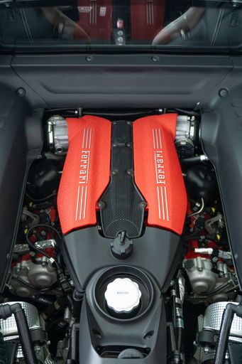 A vertical shot of a Ferrari 488 GTB Engine bay with red engine cover with Ferrari logo