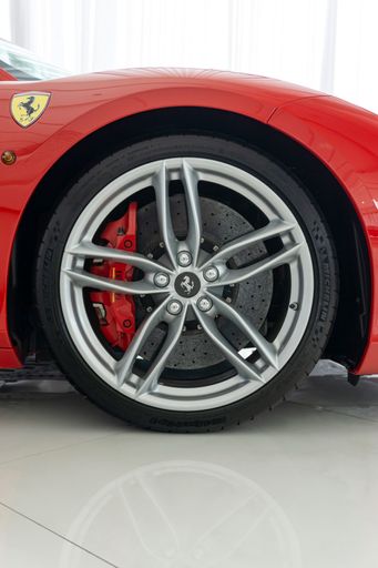 A vertical shot of a Ferrari 488 GTB Rosso Corsa with a silver wheel with carbon hub cap