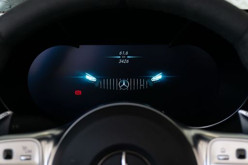 A closeup of the digital gauge cluster of a Mercedes Benz AMG GTC with artwork on its display