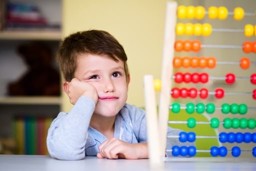A Caucasian toddler boy feeling bored and tired while playing with abacus at kindergarten