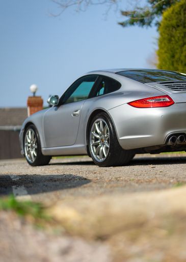 A vertical shot of the back of grey modern Porsche 911 parked on the street