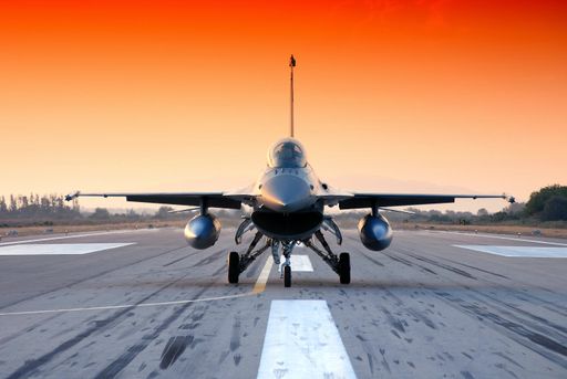 An airplane landing on the asphalt runway on the sunset