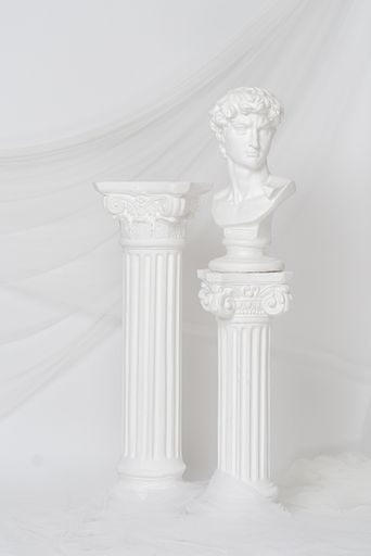 A vertical shot of the Renaissance epoch gypsum statues arranged with fabric on white background