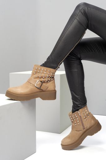 a vertical shot of female legs with black tight pants and brown boots in a sitting position - left foot raised on a cube