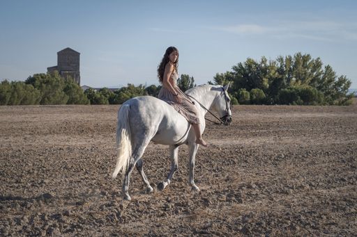 An attractive female riding a horse through the farm