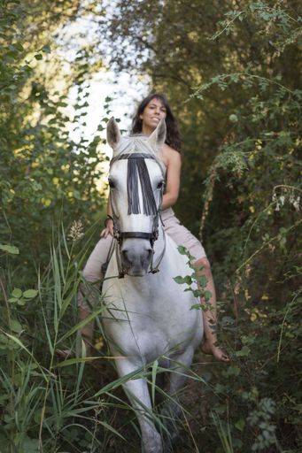 A vertical shot of an attractive female riding a horse through the field