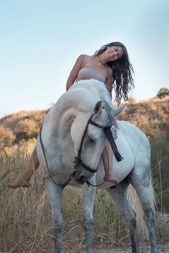 A vertical shot of an attractive female riding a horse through the field