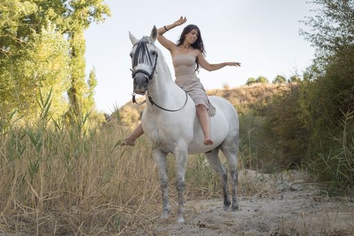An attractive female riding a horse through the farm