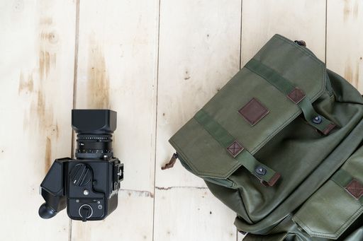 A top view of a backpack and a camera on the wooden surface - travel concept
