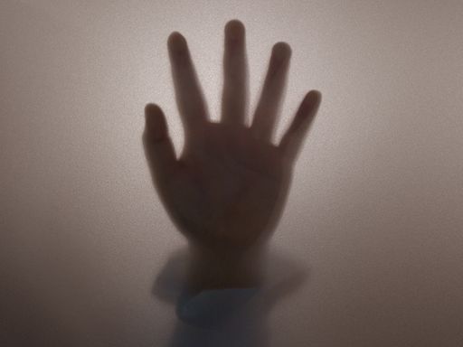 A closeup shot of female hand behind frosted glass