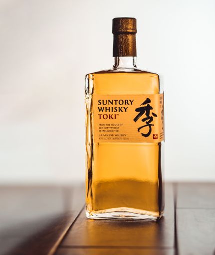 A selective focus of a bottle of Japanese Suntory Toky whiskey on a table against a white background