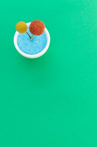 A vertical top view shot of an artificial flower on an isolated green background