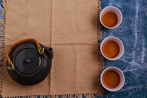 A top view of a gray tea set on a decorative brown fabric