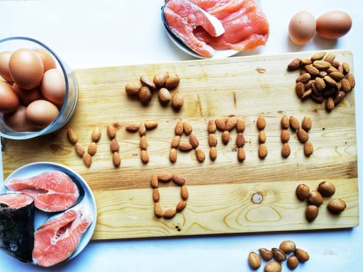 A top view shot of sliced fish, a bowl of eggs, and almond nuts formed a vitamin D on a wooden board