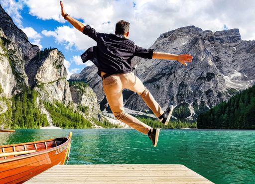 A back view of a man jumping on wooden pier in the Fanes-Sennes-Prags Nature Park in Italy