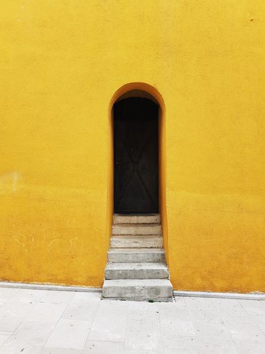 A vertical shot of an arch doorway of a building with bright yellow exterior walls