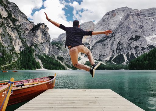 A back view of a man jumping on wooden pier in the Fanes-Sennes-Prags Nature Park in Italy